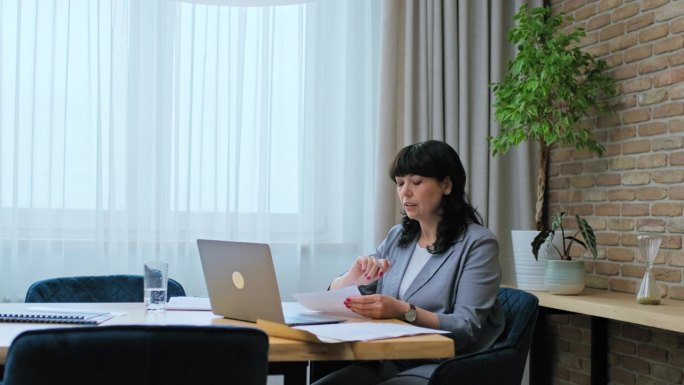 成熟的商务女性在工作场所使用笔记本电脑进行虚拟视频会议