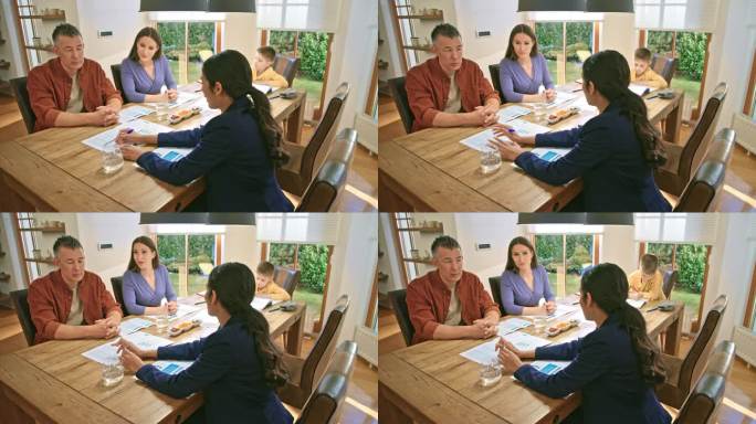 一对夫妇坐在餐桌旁与一位女保险代理人交谈