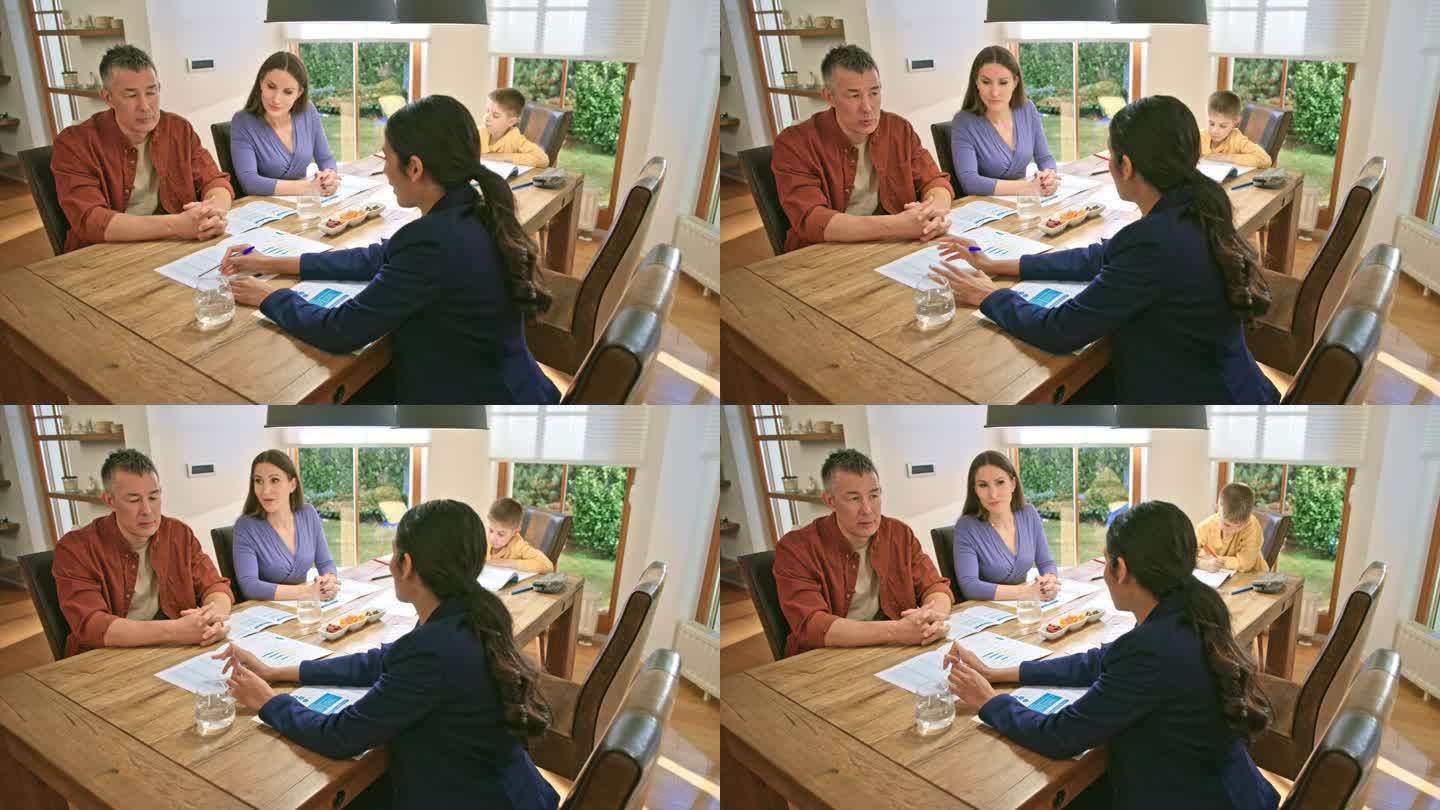 一对夫妇坐在餐桌旁与一位女保险代理人交谈