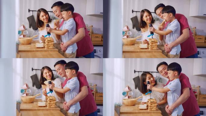 漂亮的亚洲夫妇带着年幼的儿子在家里的厨房里烤面包。幸福的家庭，爸爸和妈妈花时间和小儿子一起做巧克力面