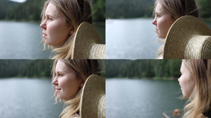一个女孩的侧面特写，看着山里的一个湖。一个肩上戴草帽的女人。旅游