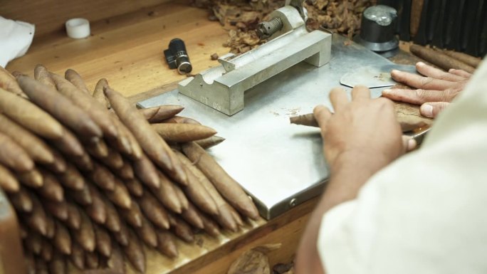 在卷烟厂的桌子上，男性用干烟叶制作雪茄的全过程特写。切、扭、粘。叠好的手工成品。60fps 4k镜头