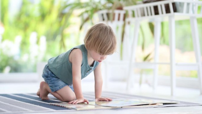 可爱的小男孩在家里地板上看书。日间护理创意活动。孩子们玩得很开心。教育学习游戏。家庭休闲室内。