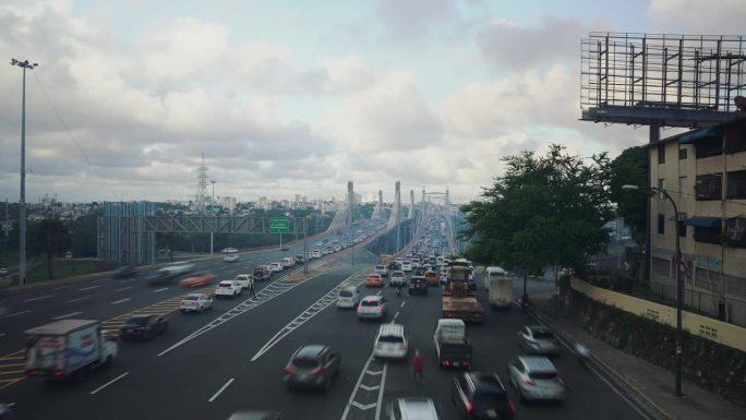 圣多明各胡安博世大桥上的多车道高速公路上，许多汽车和卡车在高峰时间晚上快速行驶的广角延时。模糊运动城