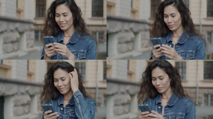 美丽的亚洲女人用智能手机触摸屏和微笑站在城市街道的肖像