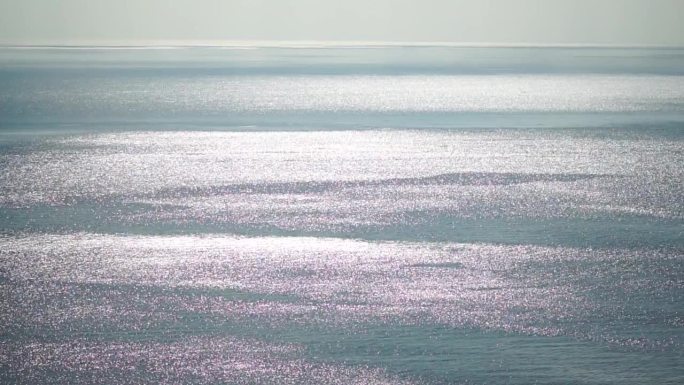 抽象空中大海夏天海洋日落自然背景。平静水面上的小波浪在运动中与太阳的金色散景灯模糊。度假、度假、休闲