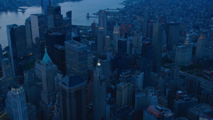 直升机夜游纽约市建筑。飞越曼哈顿与灯光和哈德逊河为背景的华尔街办公大楼全景