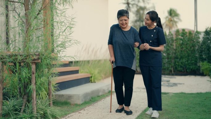 护理人员协助老年妇女使用手杖进行家庭保健|老年人的支持和独立性