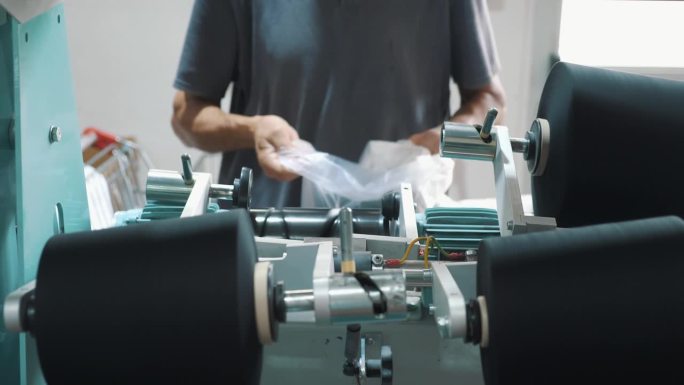 一名工人正在打包成卷的纱线。纺织厂设备。纺织工厂。纺纱生产。纱线制作工艺。线生产。