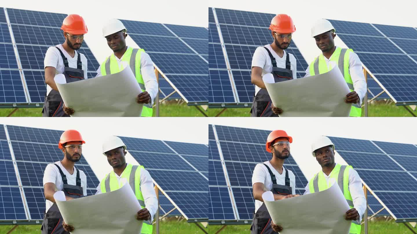 年轻的非洲工程师和印度技术人员站在那里，计划安装太阳能电池板。产业工人讨论安装太阳能系统