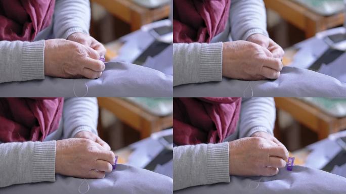 一位老妇人用针线手工缝纫的特写。有选择性的重点。