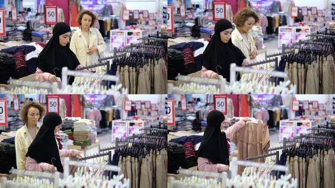 两位顾客在女装店里挑选东西、购物。戴着头巾的穆斯林妇女在精品店看衬衫、t恤和衬衫。不同国籍的顾客在店