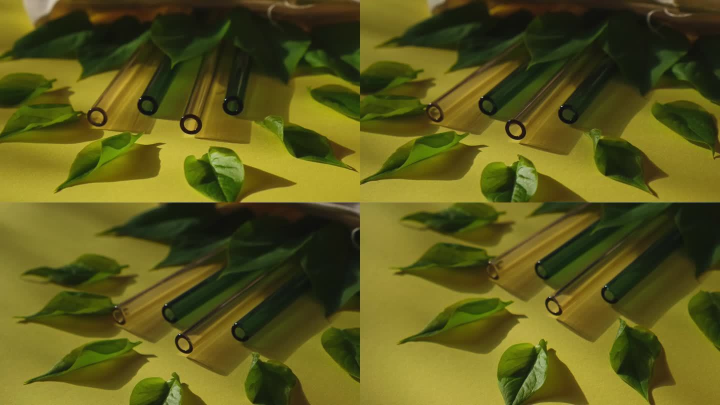 可重复使用的玻璃吸管彩色背景与绿色的叶子在环保袋环保吸管集可重复使用舒适的圆形尖端吸管。零废弃物，无