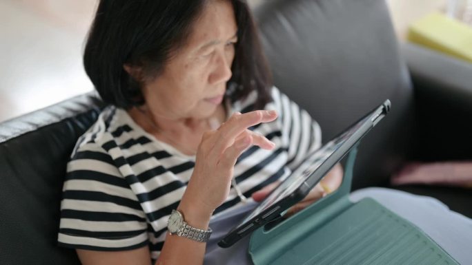一个单身的亚洲老人在家里和朋友在社交媒体上发短信