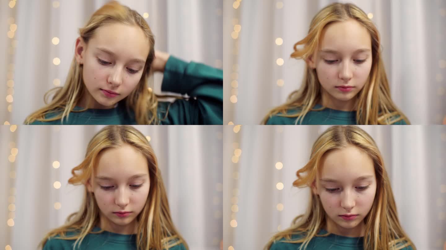 金发少女的肖像在家里抚摸头发看着相机和向下。