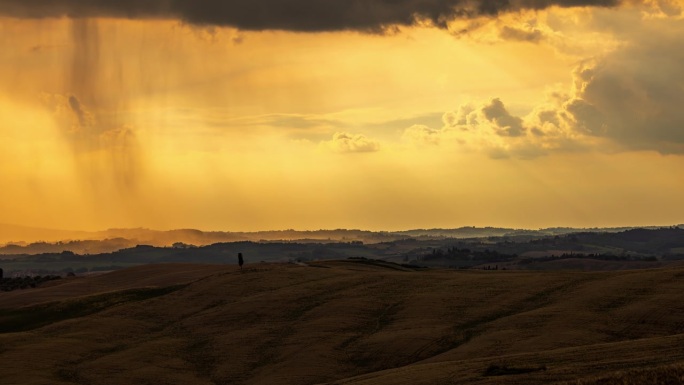 托斯卡纳日出时，云彩在田园诗般的金色风景上移动