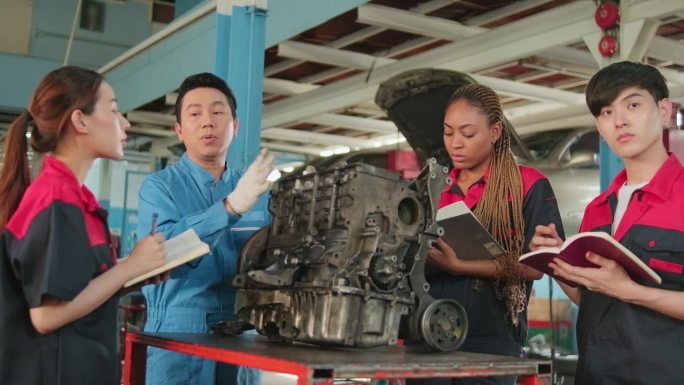 主管工程师正在汽车修理厂教机械工人有关汽车发动机的知识。