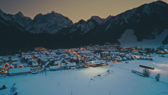 航拍黄昏时分，朱利安阿尔卑斯山的雪山环绕着克拉尼斯卡戈拉镇