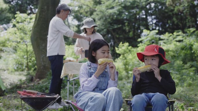 日本小孩在露营时吃玉米
