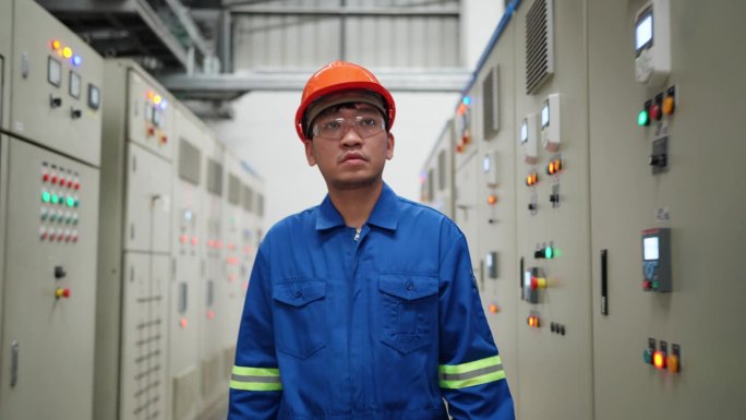 专业技术工程师自信地走在一家石油工厂的开关柜里，勤奋地监视着电气状态。分析和优化电气状态，举例说明它
