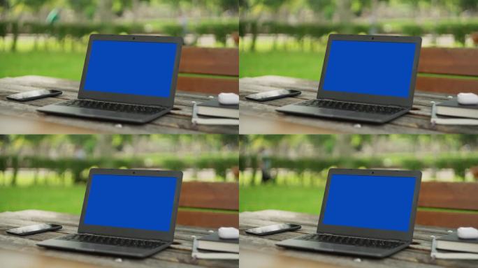 笔记本电脑和几本书放在户外的桌子上，彩色键蓝屏