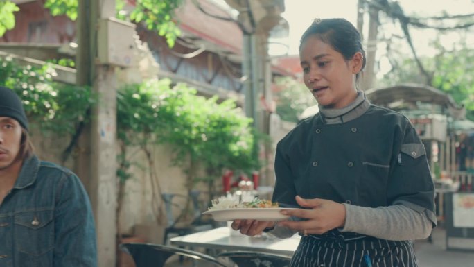 在充满活力的泰国街头市场，女厨师为游客提供正宗的泰式炒粉。