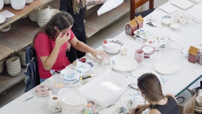 陶瓷厂的工人们在桌子上给陶瓷添加图案