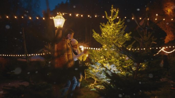 一对夫妇在圣诞树上挂装饰品时玩得很开心