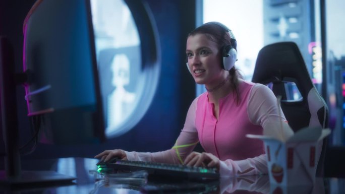 年轻女子穿着新潮的衣服，化着鲜绿色的妆，戴着霓虹灯戒指，在台式电脑上玩电子游戏。美丽的女孩在她的未来