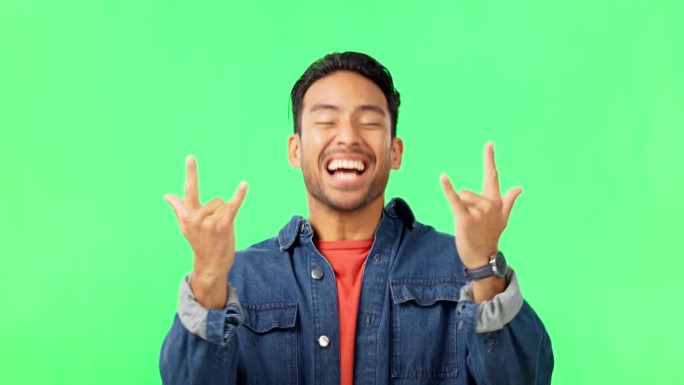一个男人用摇滚的手势在绿色屏幕上听重金属音乐，播放列表或专辑。快乐，肖像和男模特与朋克标志流的垃圾歌