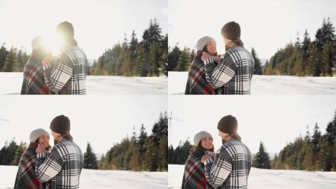 爱情、幸福和假期是这对情侣在冬天散步的镜头。相爱的男孩和女孩浪漫地站在夕阳下的雪中。男人用毯子盖住女