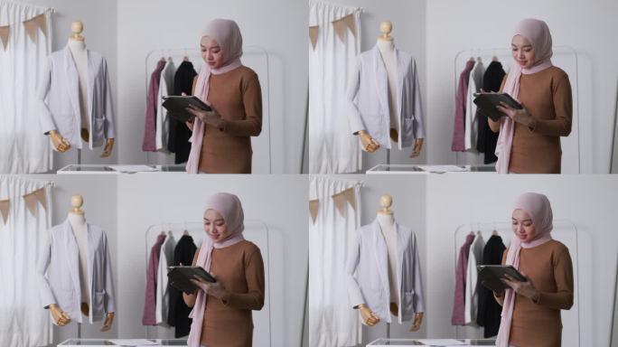 穆斯林时装设计师与休闲使用数字平板电脑创建新的系列在她的商店直播