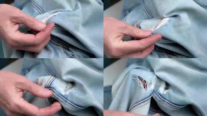 裁缝的手检查女士牛仔裤腿间的洞的特写。