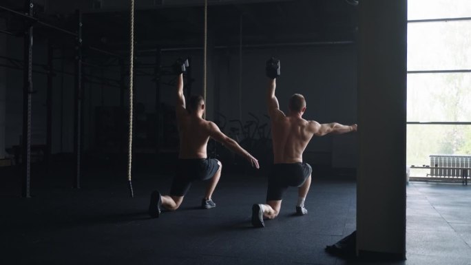 一对举重运动员一起训练，在健身房用哑铃做练习，后视图