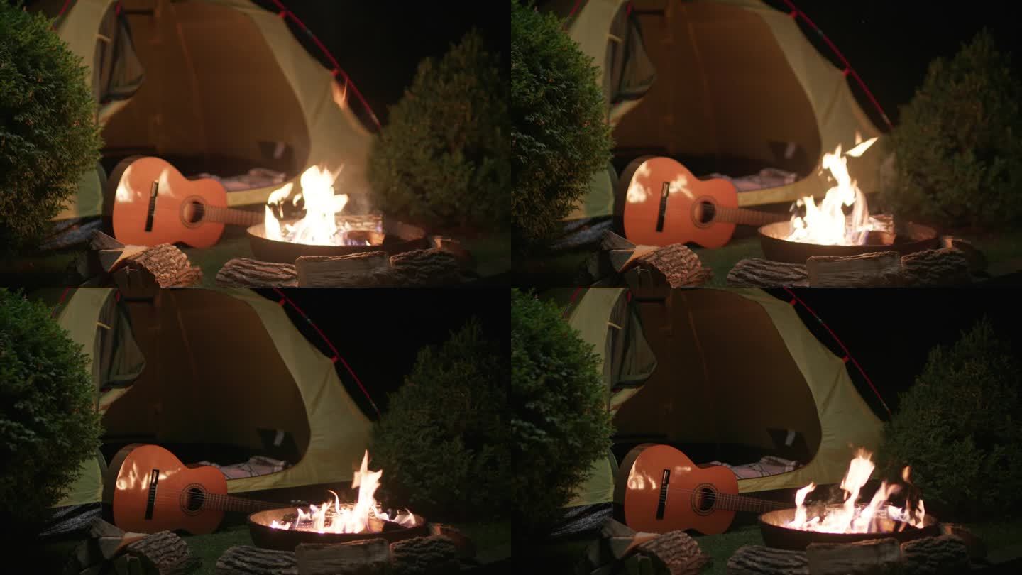 篝火旁的吉他和黑暗中的帐篷。晚上没有人的露营地。