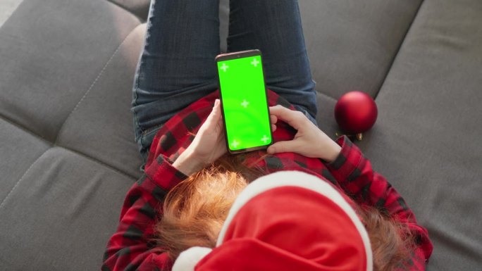 一个头戴红色圣诞老人帽的时尚女孩正在网上为她所爱的人挑选冬季和圣诞节的最佳礼物。福塔奇效应铬绿ekr