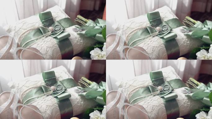 两枚白金结婚戒指，枕头上系着绿丝带，放在木桌上。婚礼的细节