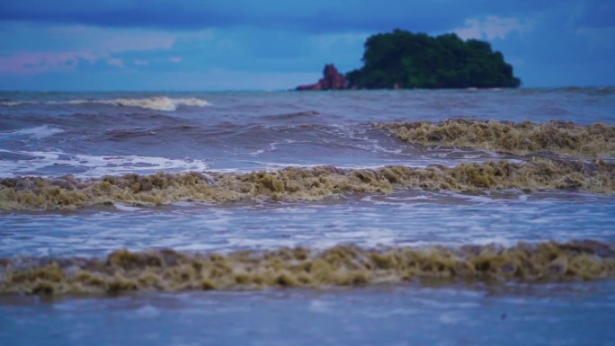 大海里的大浪打在沙滩上，海水浑浊。