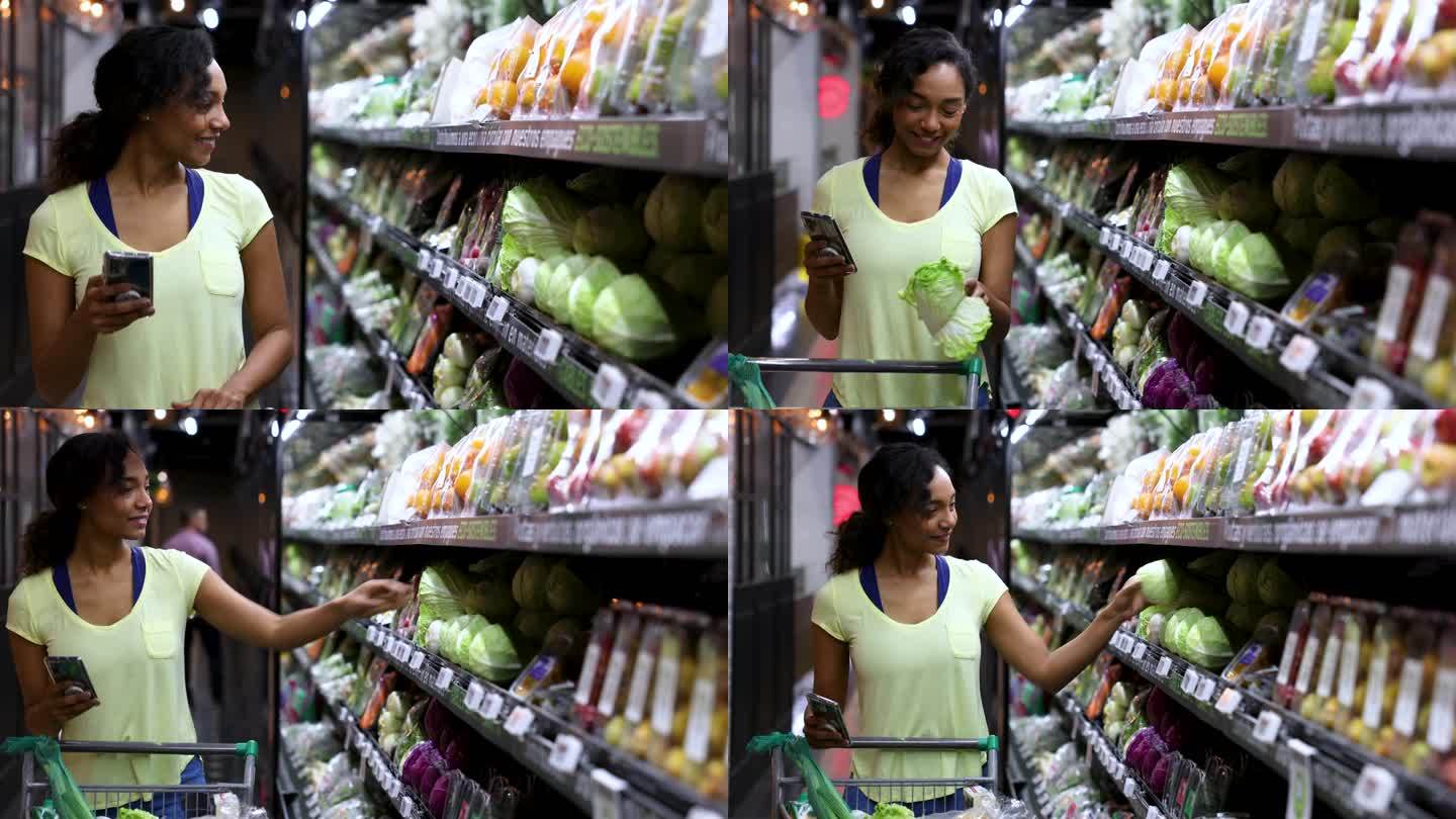 一位快乐的非裔美国妇女在超市购买健康食品，一边推着购物车一边看手机上的购物清单