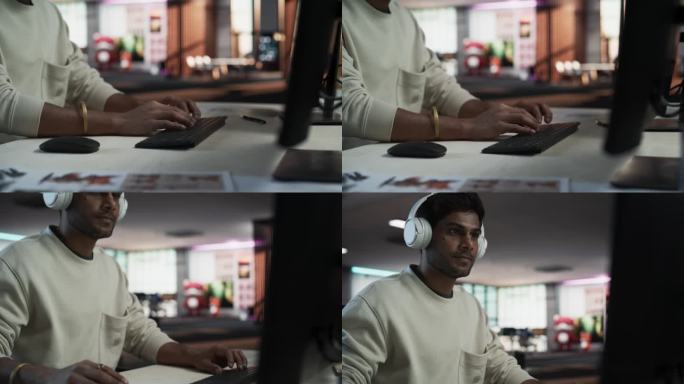 一位印度男子在公司办公室的台式电脑前工作的特写肖像。年轻男经理上网、网上购物、阅读朋友和同事的社交媒