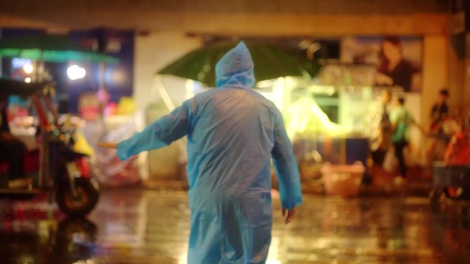 一个年轻人正在过马路，而在市中心的晚上下着大雨。