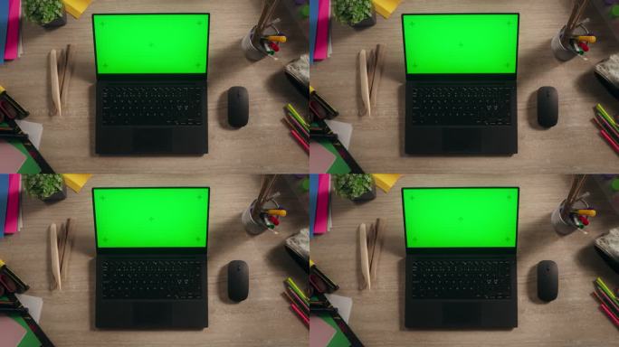 笔记本电脑的顶部静态视图与模拟绿屏Chromakey显示器站在桌子上的创意工作室无线鼠标，彩色蜡笔和