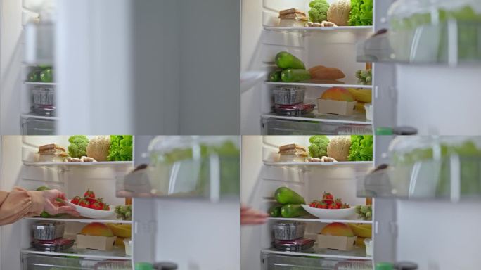 LD女性的手把一个装有西红柿的盘子放在冰箱的架子上
