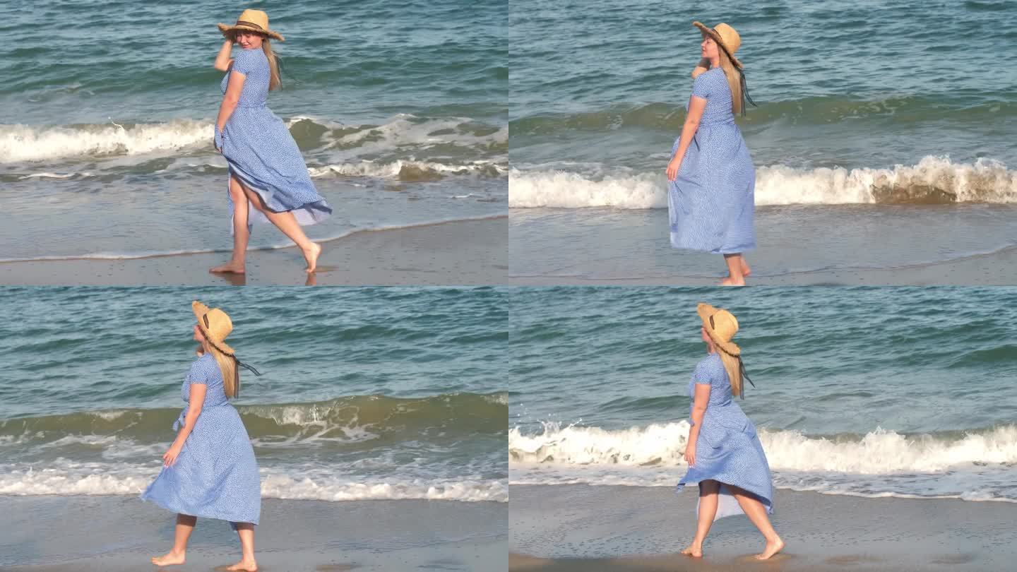 一位金发碧眼、身穿蓝色长裙的年轻漂亮女子沿着海滩散步。穿蓝裙子的女孩。长长的红裙子在风中飘动