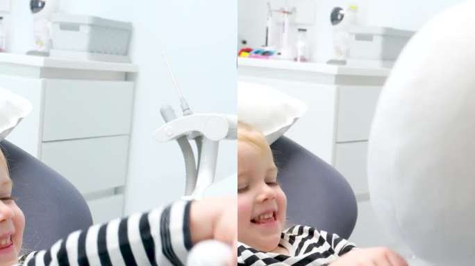一个4.5岁的女孩在牙科椅上玩一个毛绒玩具，一个疯子天线宝宝或一个宇航员，她挥手，它看起来微笑放松等