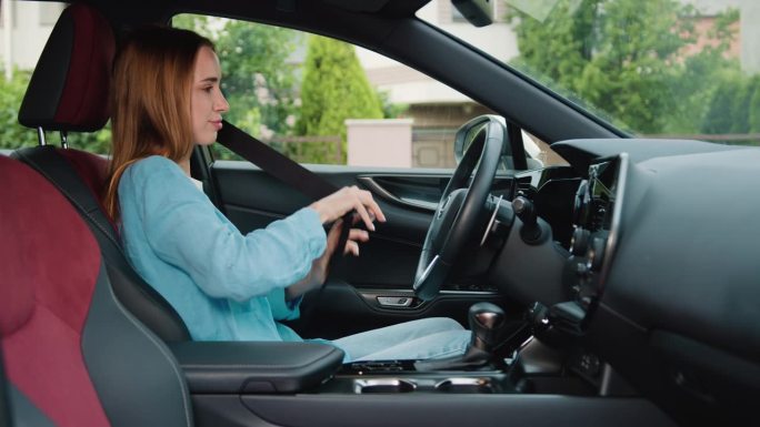 坐在汽车驾驶座上系安全带的妇女触摸方向盘。小女孩坐在现代汽车里系上安全带。女性购车者选择新车。