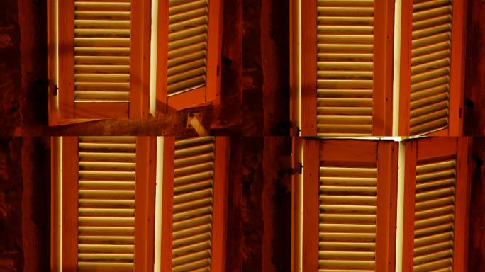 老岩石房子里的木制百叶窗。意大利风格的百叶窗从里面发出淡蓝色的光，晚上从外面发出淡黄色的街灯。202