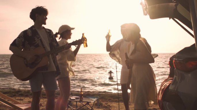 一群朋友在海边露营时载歌载舞，在海滩上享受假日假期旅行