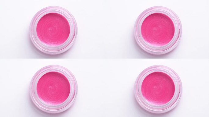 粉色眼影在白色背景上旋转。化妆品的广告。化妆品液体唇彩或腮红