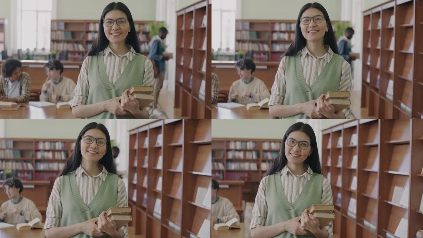 一个无忧无虑的亚洲女孩，戴着眼镜，穿着时髦的衣服，站在大学图书馆里拿着书